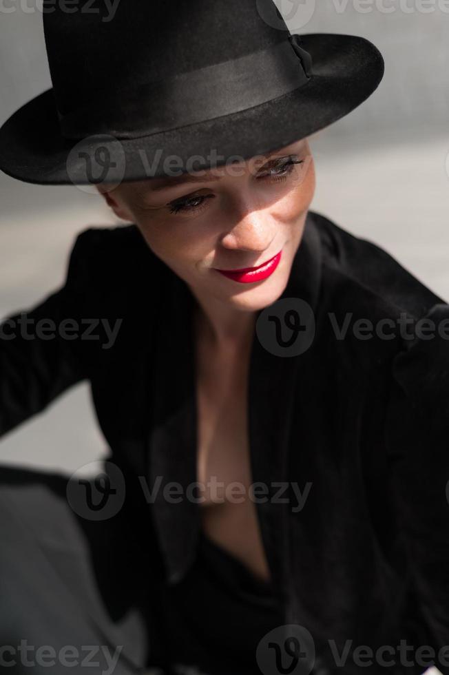 Girl posing in a black hat on the background of sunlight photo