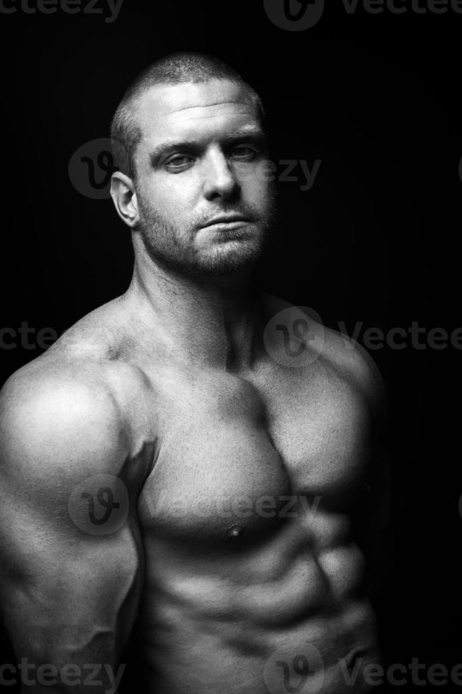 sports man standing on a black background, doing sports photo
