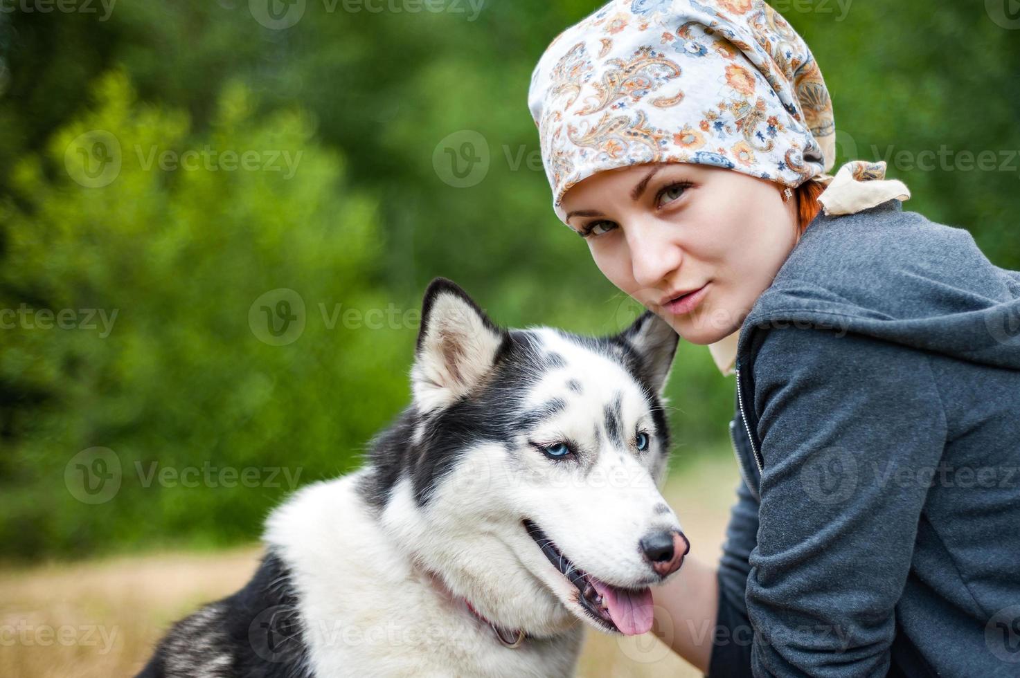 una niña mientras caminaba por el parque con un perro, abrazando al perro husky y besándose. foto