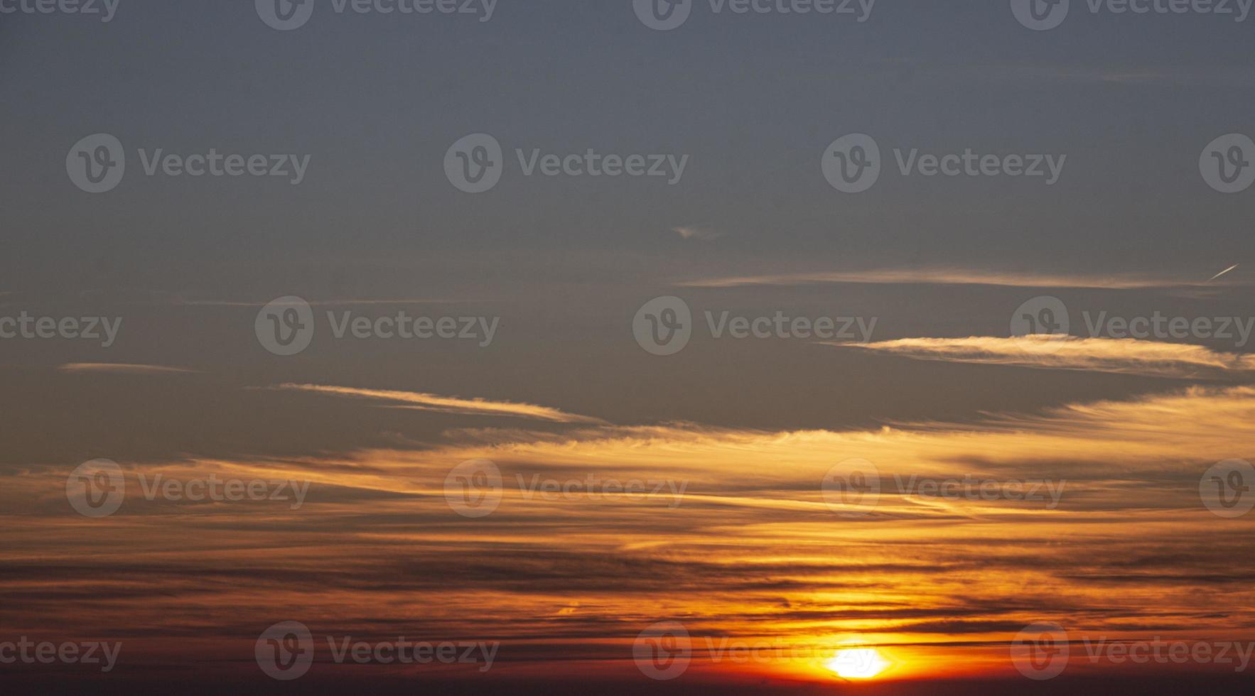 imagen de cielo dramático y colorido con sol durante la puesta de sol foto