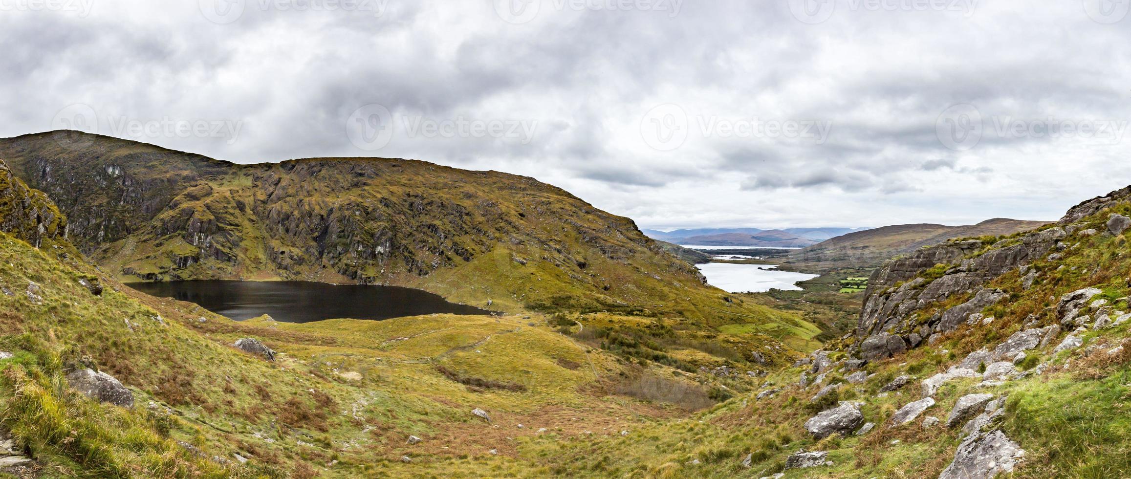 Panorama picture of typical Irish landscape with green meadows and rough mountains during daytime photo