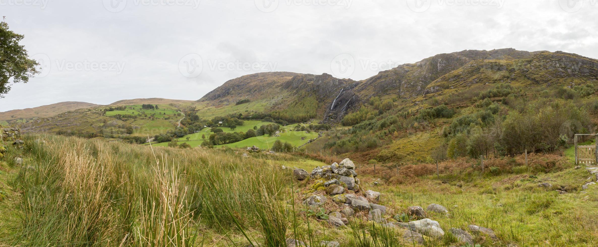 Panorama picture of typical Irish landscape with green meadows and rough mountains during daytime photo