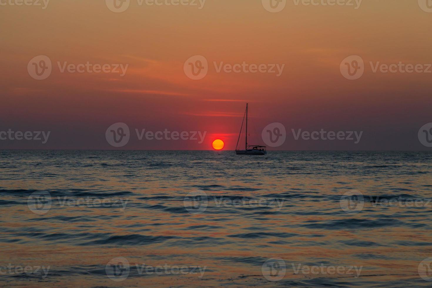 Sunset over the sea with boat silhouette photo