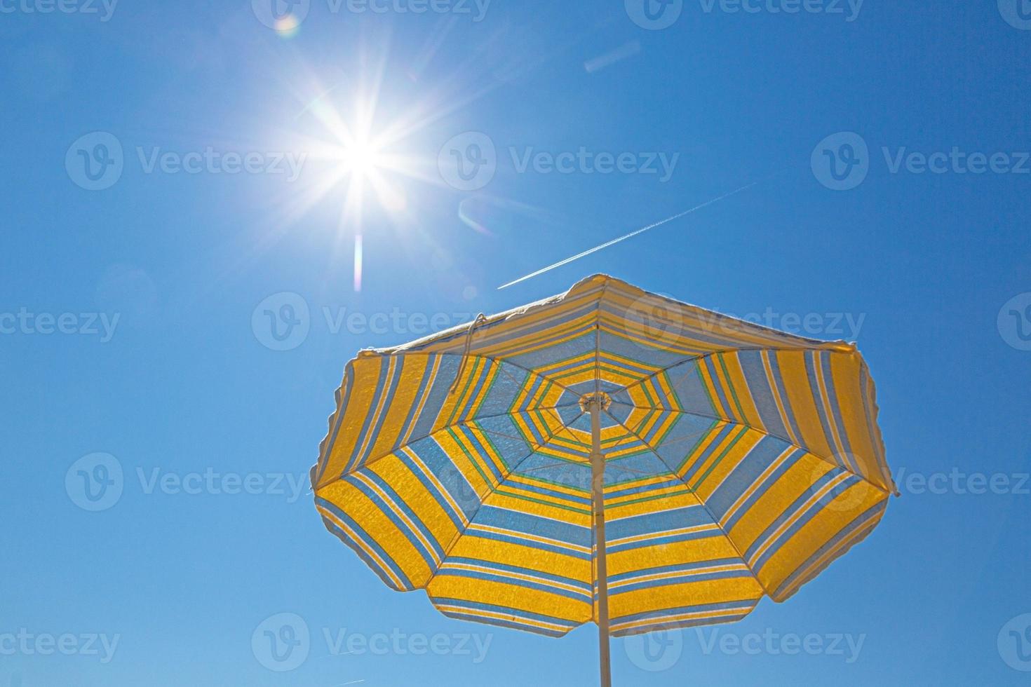 imagen de una sombrilla de color azul amarillo frente a un cielo azul brillante foto