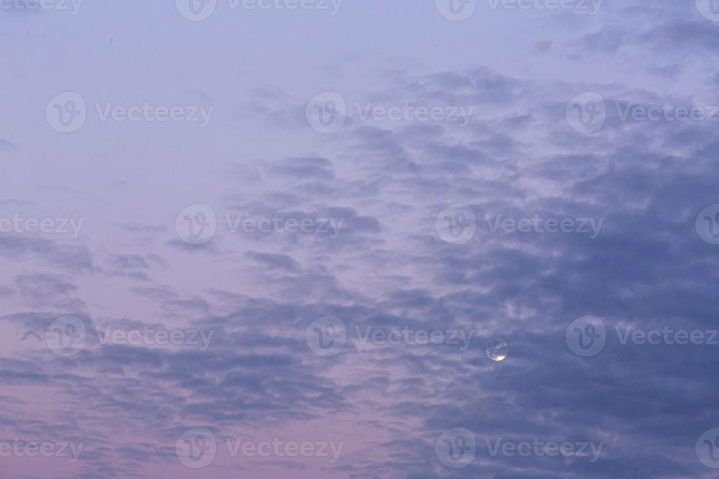 Image of full moon against colorful evening sky with light clouds photo
