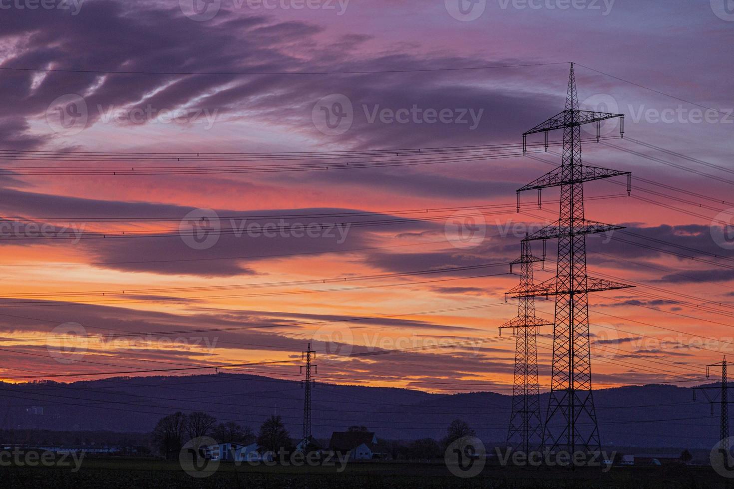 Image of a colorful and high-contrast sunrise with bright cloud formations and contours of power poles photo