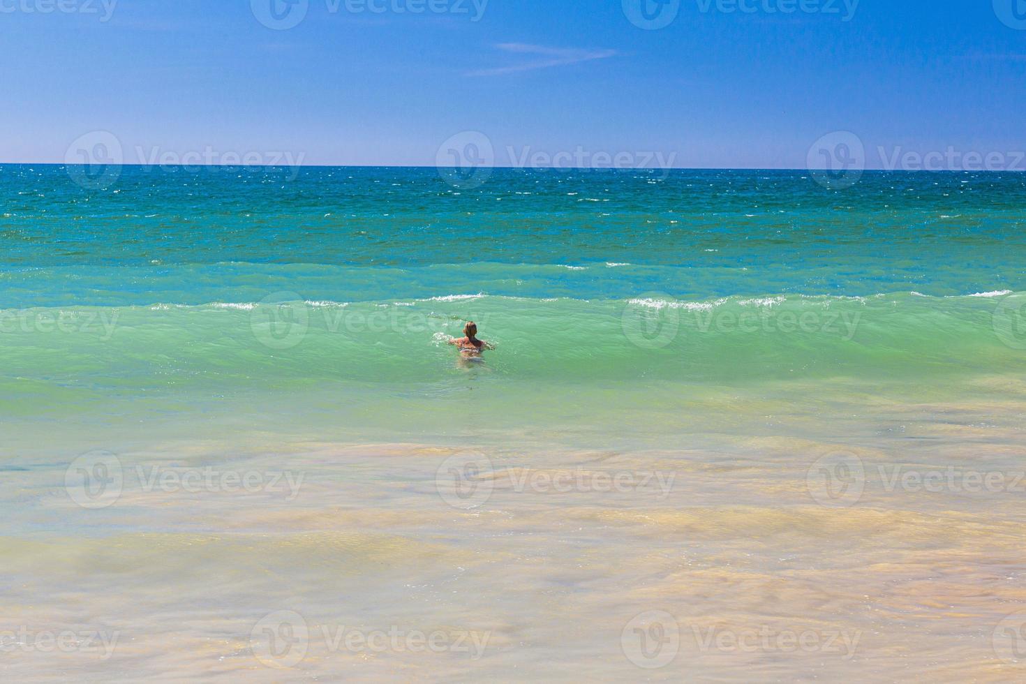 Swimming person in turquoise waters at Algharve coast in Portugal in summer photo
