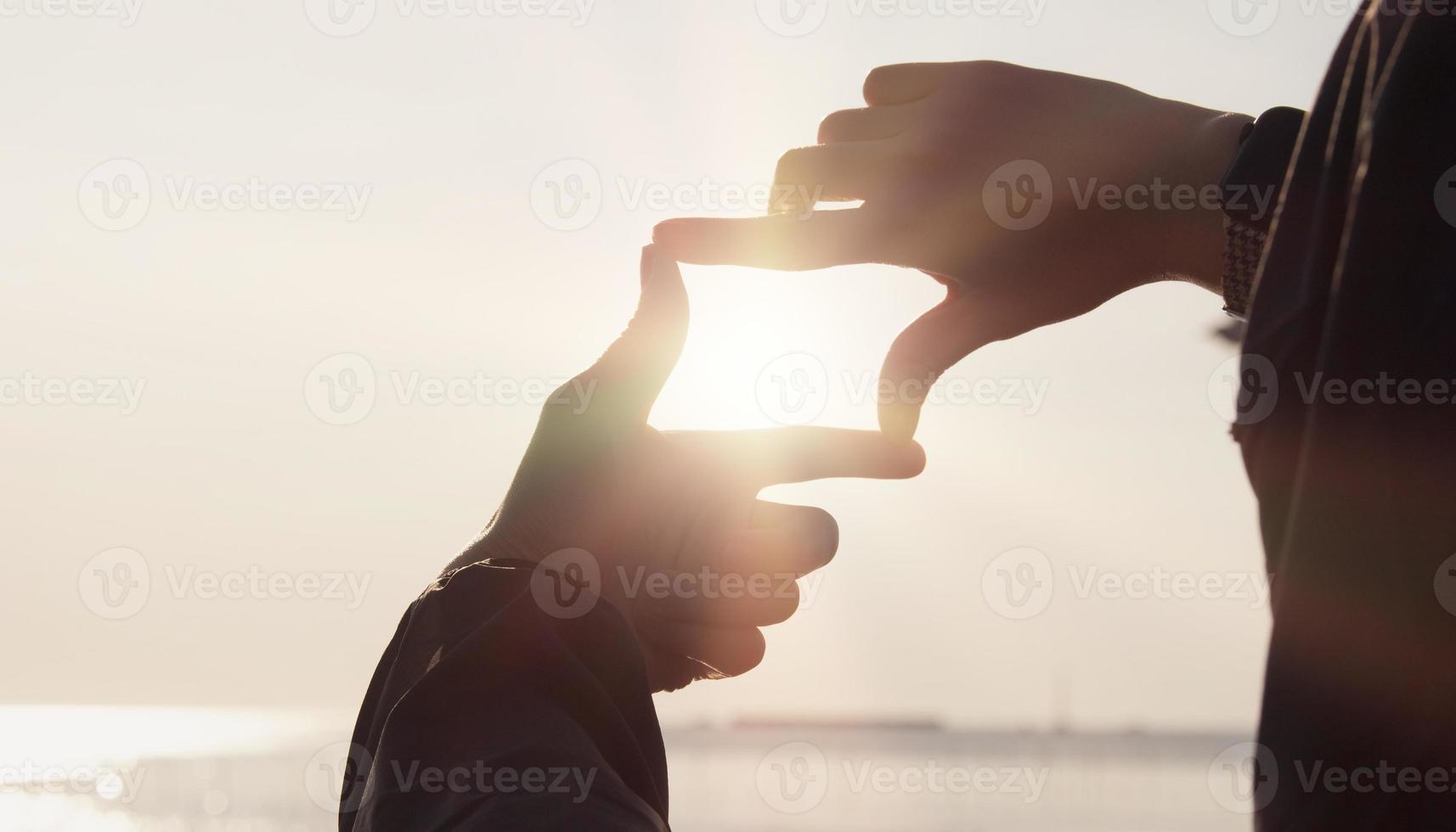 Planning and vision concept of new year's start, woman hands making frame gesture find focus at sunset, woman looking for perspective to capture the meaning of a clear upcoming target. photo