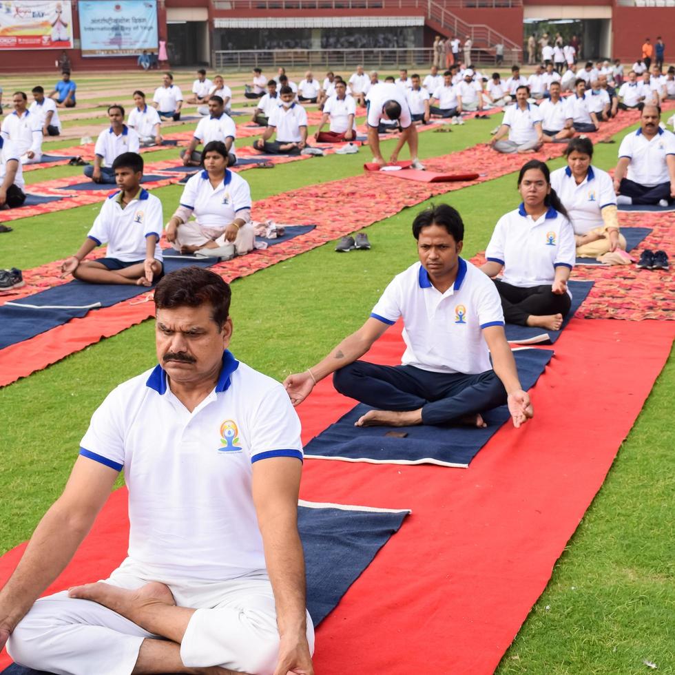 New Delhi, India, June 21 2022 - Group Yoga exercise session for people at Yamuna Sports Complex in Delhi on International Yoga Day, Big group of adults attending yoga class in cricket stadium photo