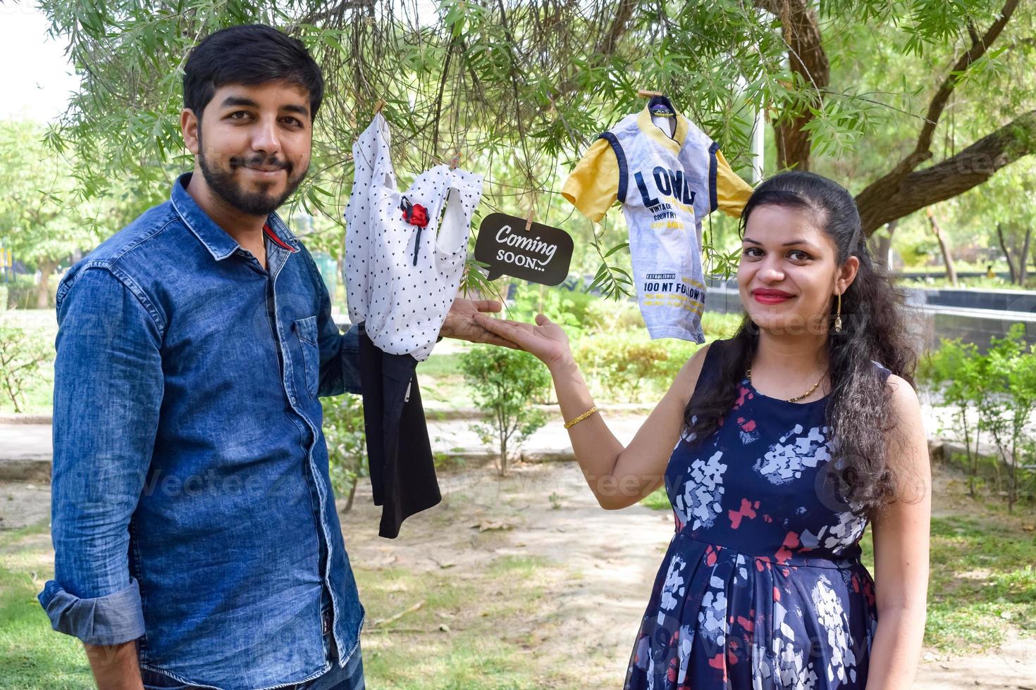 Indian couple posing for maternity baby shoot. The couple is posing in a lawn with green grass and the woman is falunting her baby bump in Lodhi Garden in New Delhi, India photo