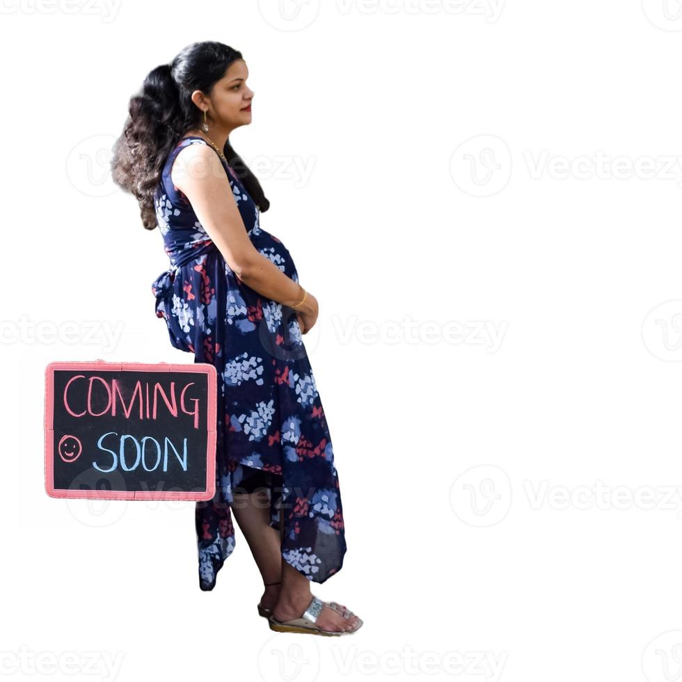 Indian couple posing for maternity baby shoot with white plain background. The couple is posing in a lawn with green grass and the woman is falunting her baby bump in Lodhi Garden in New Delhi, India photo