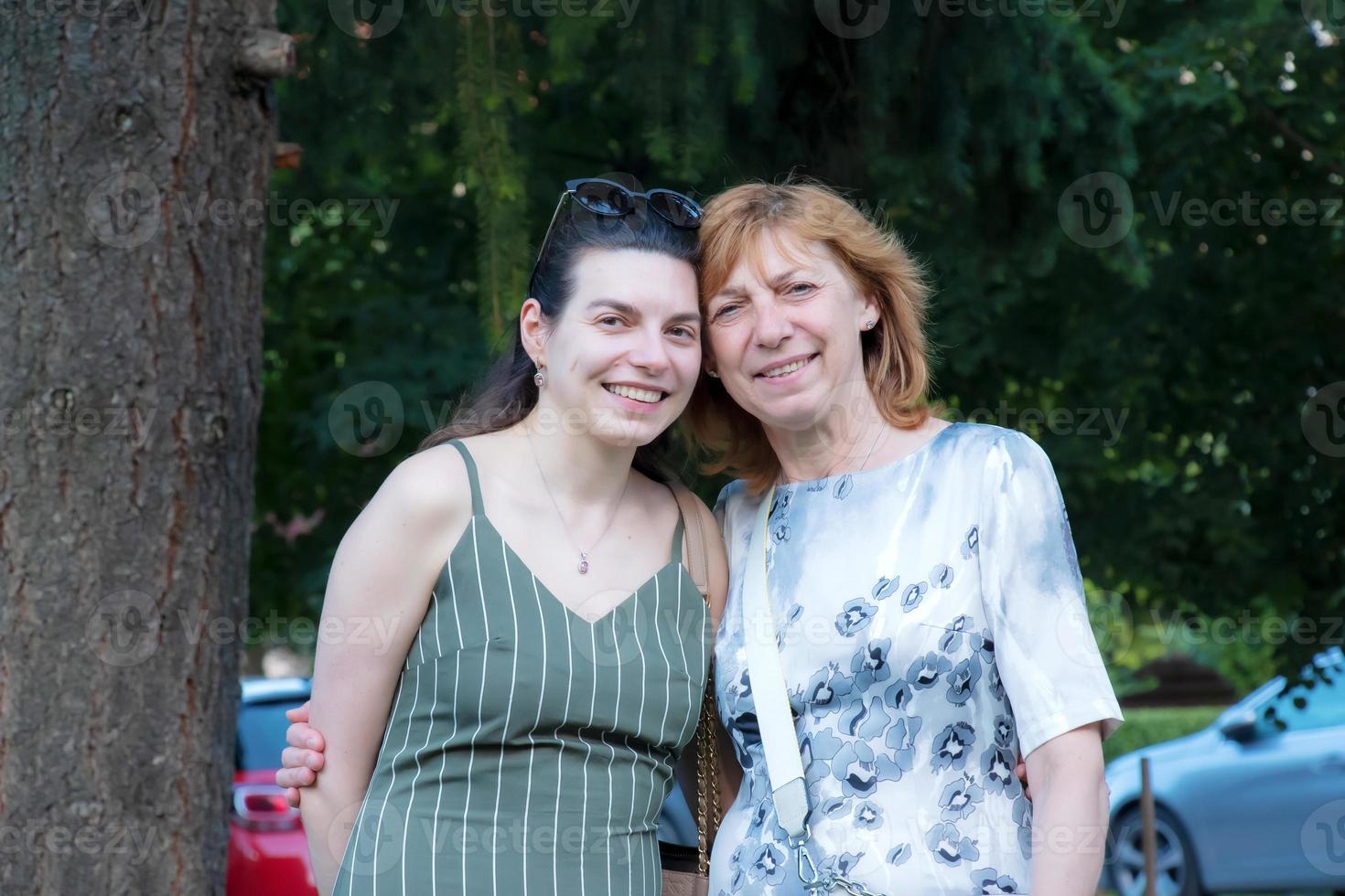Beautiful senior mother and her adult daughter look at the camera and smile photo