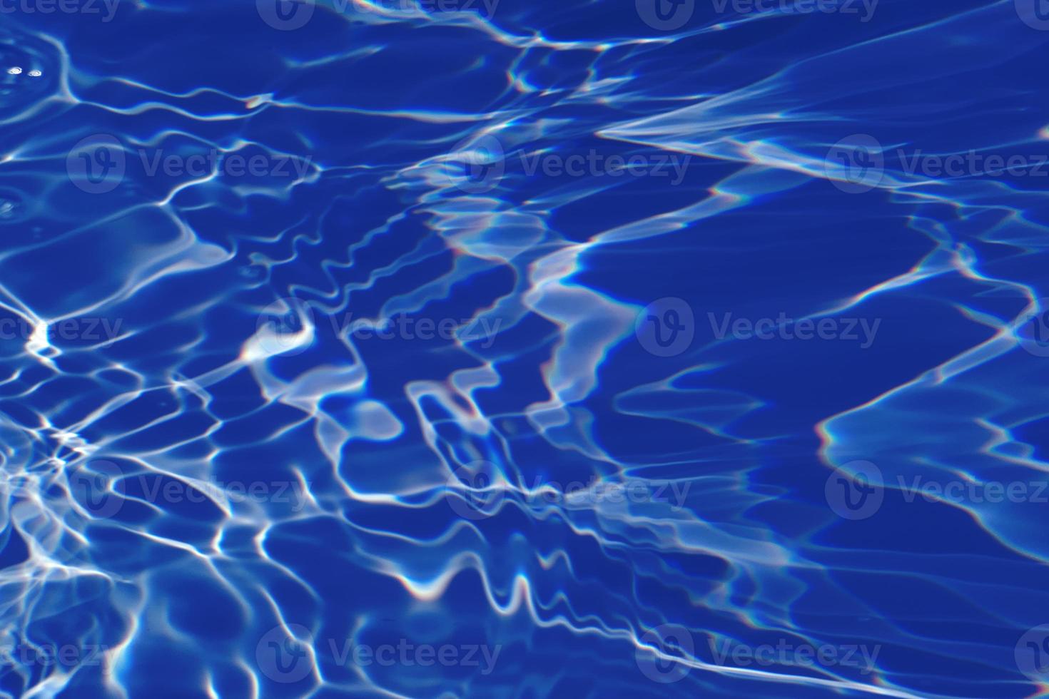 Defocus blurred transparent blue colored clear calm water surface texture with splashes and bubbles. Trendy abstract nature background. Water waves in sunlight with caustics. Blue water shinning photo