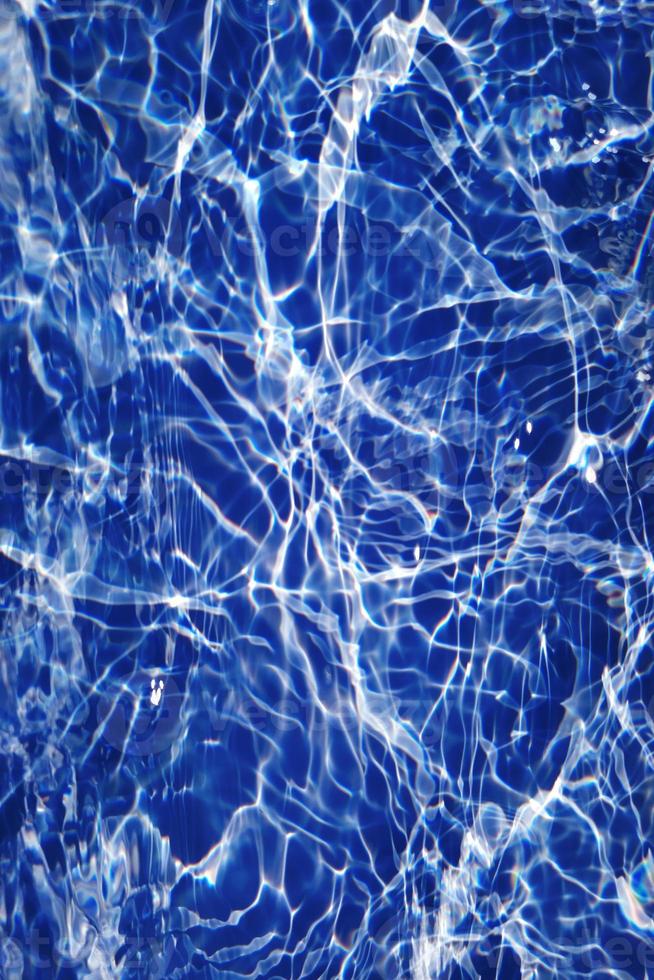 desenfoque borroso transparente color azul claro agua tranquila textura superficial con salpicaduras y burbujas. fondo de naturaleza abstracta de moda. ondas de agua a la luz del sol con cáusticos. agua azul brillando foto