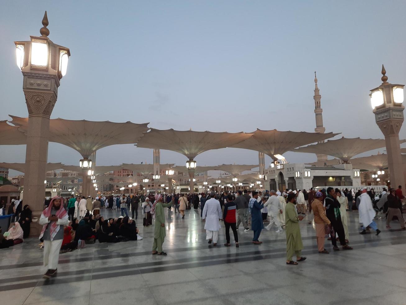 medina, arabia saudita, diciembre de 2022 - hermosa vista nocturna en masjid al-nabawi, los visitantes son vistos en las luces de la mezquita en las instalaciones de la mezquita. foto