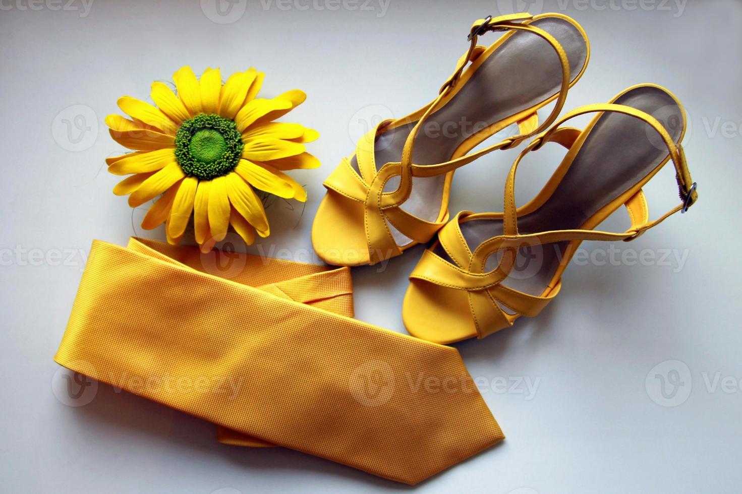 sandalias amarillas, corbata y flor para la boda en el fondo blanco. foto