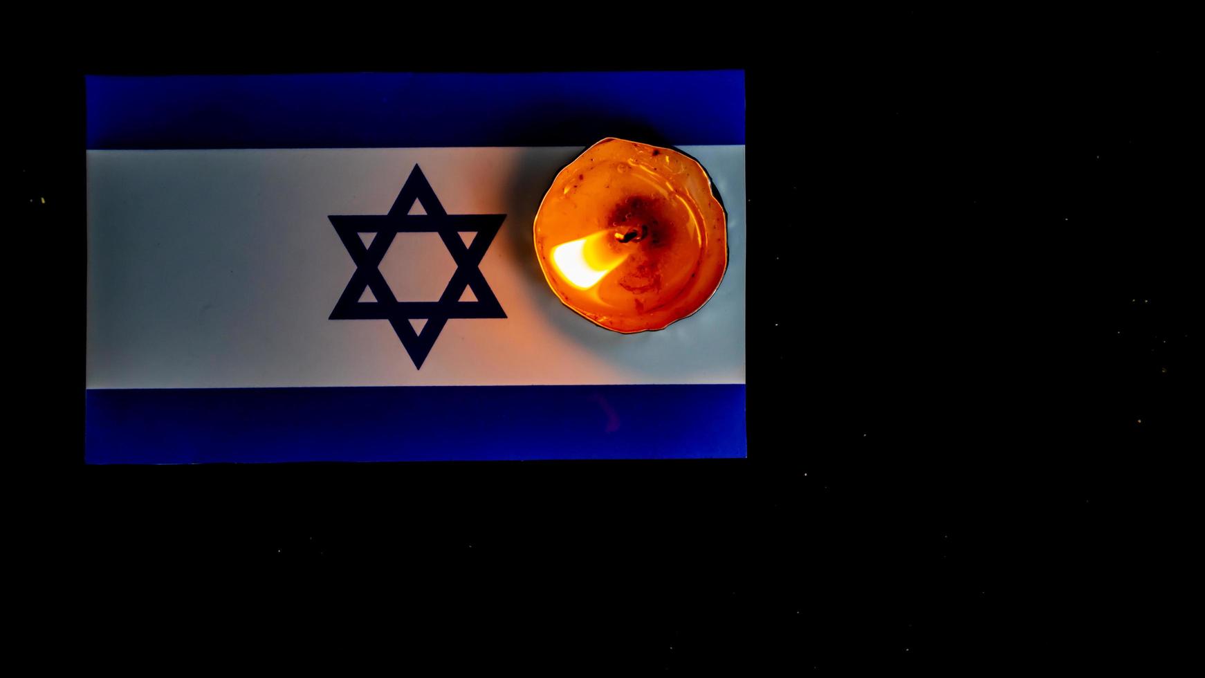 Israeli flag and candles burning above it, Holocaust memory day photo