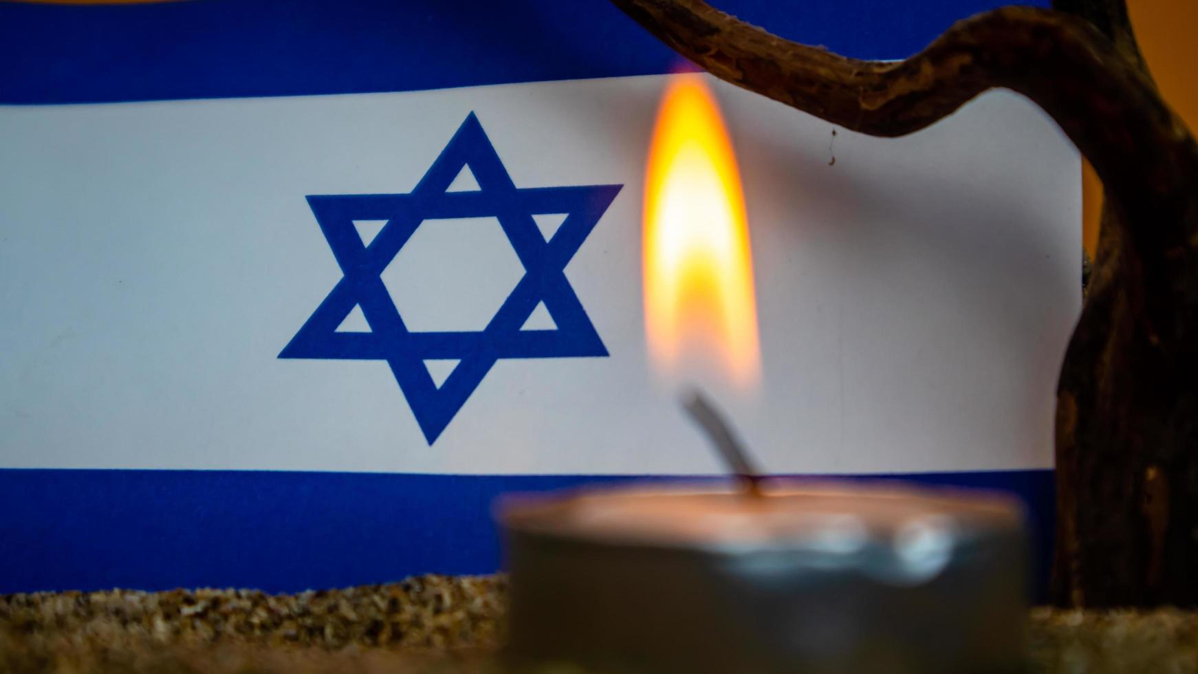 bandera israelí y velas encendidas frente a ella, día de la memoria del holocausto foto