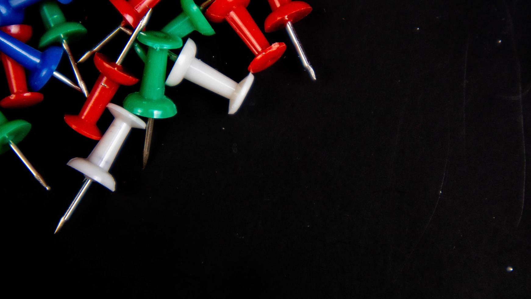 multicolored thumbtacks on a black background photo