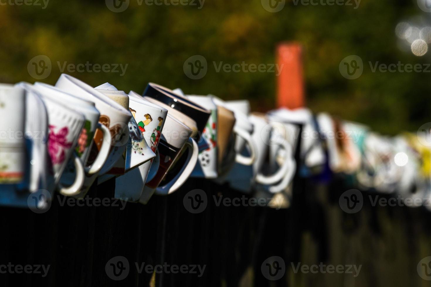 a row of coffee mugs stacked on the fence photo