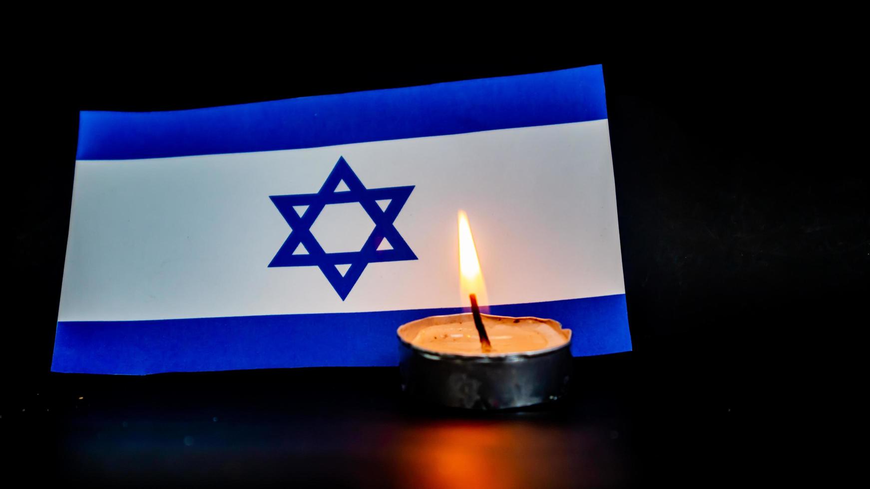 Israeli flag and candles burning in front of it, Holocaust memory day photo