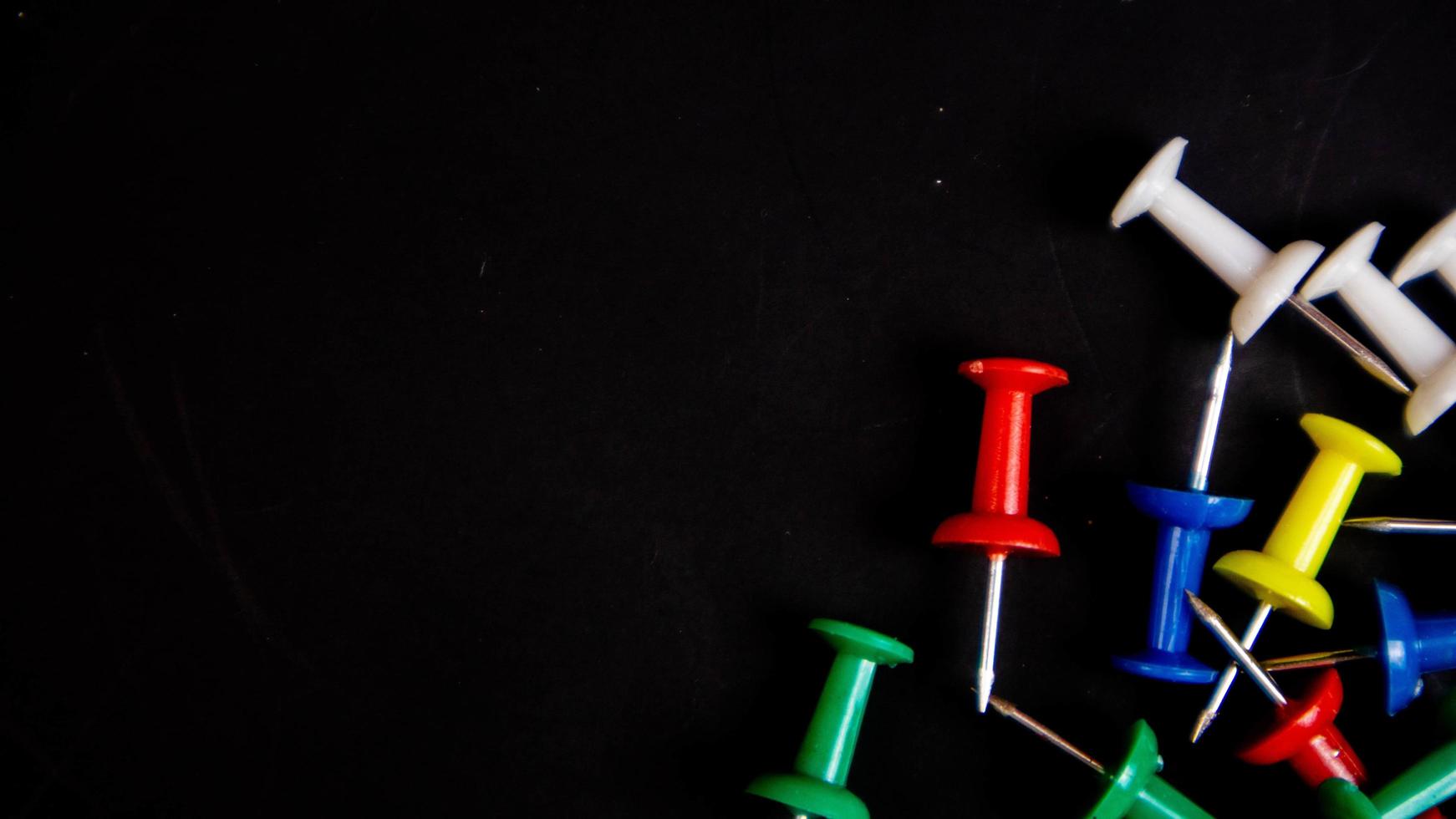 multicolored thumbtacks on a black background photo