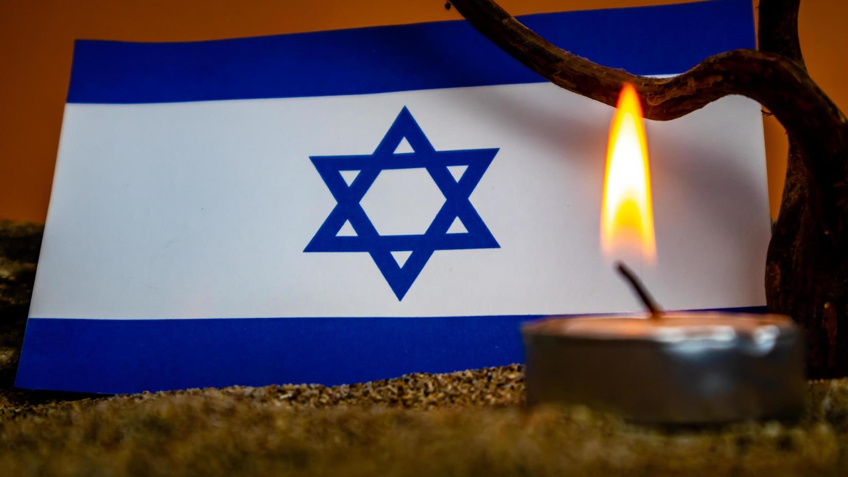 bandera israelí y velas encendidas frente a ella, día de la memoria del holocausto foto