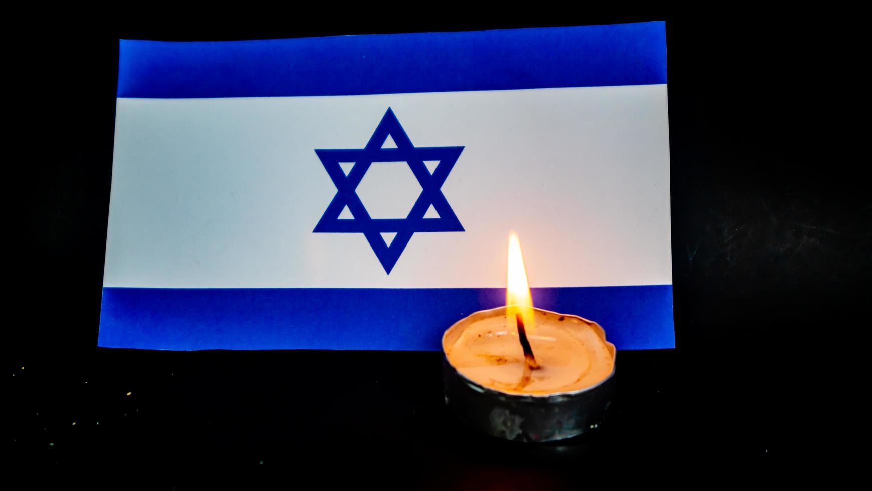 bandera israelí y velas encendidas frente a ella, día de la memoria del holocausto foto