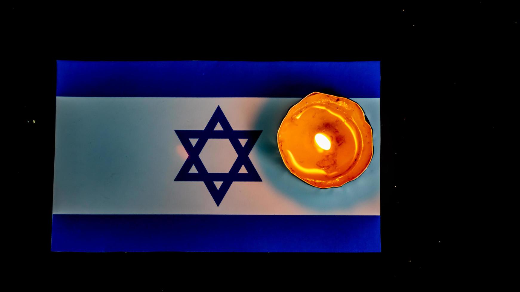 Israeli flag and candles burning above it, Holocaust memory day photo