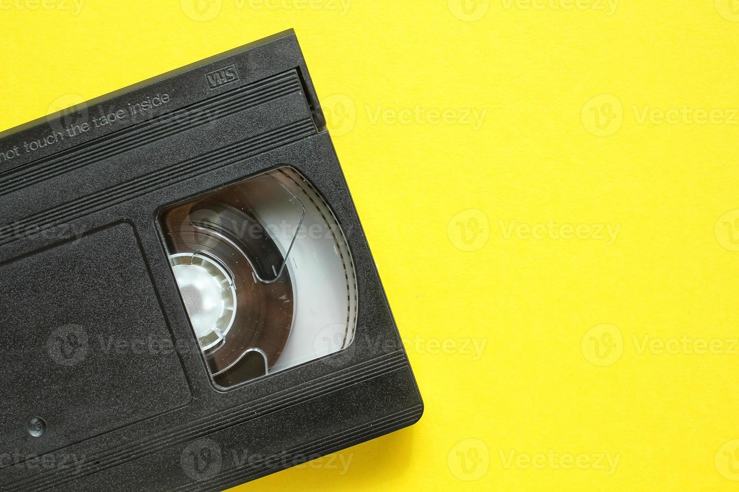 casete de grabadora de cinta de video vhs negro sobre fondo amarillo. antigua tecnología obsoleta para grabar cintas y ver películas multimedia. retro, vintage, historia, concepto de nostalgia. endecha plana, espacio de copia foto