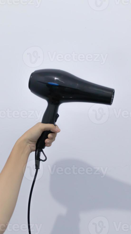 Black plastick hair dryer with black buttons in hand. Isolated on white background. Home appliance, heat air blower for salon. photo