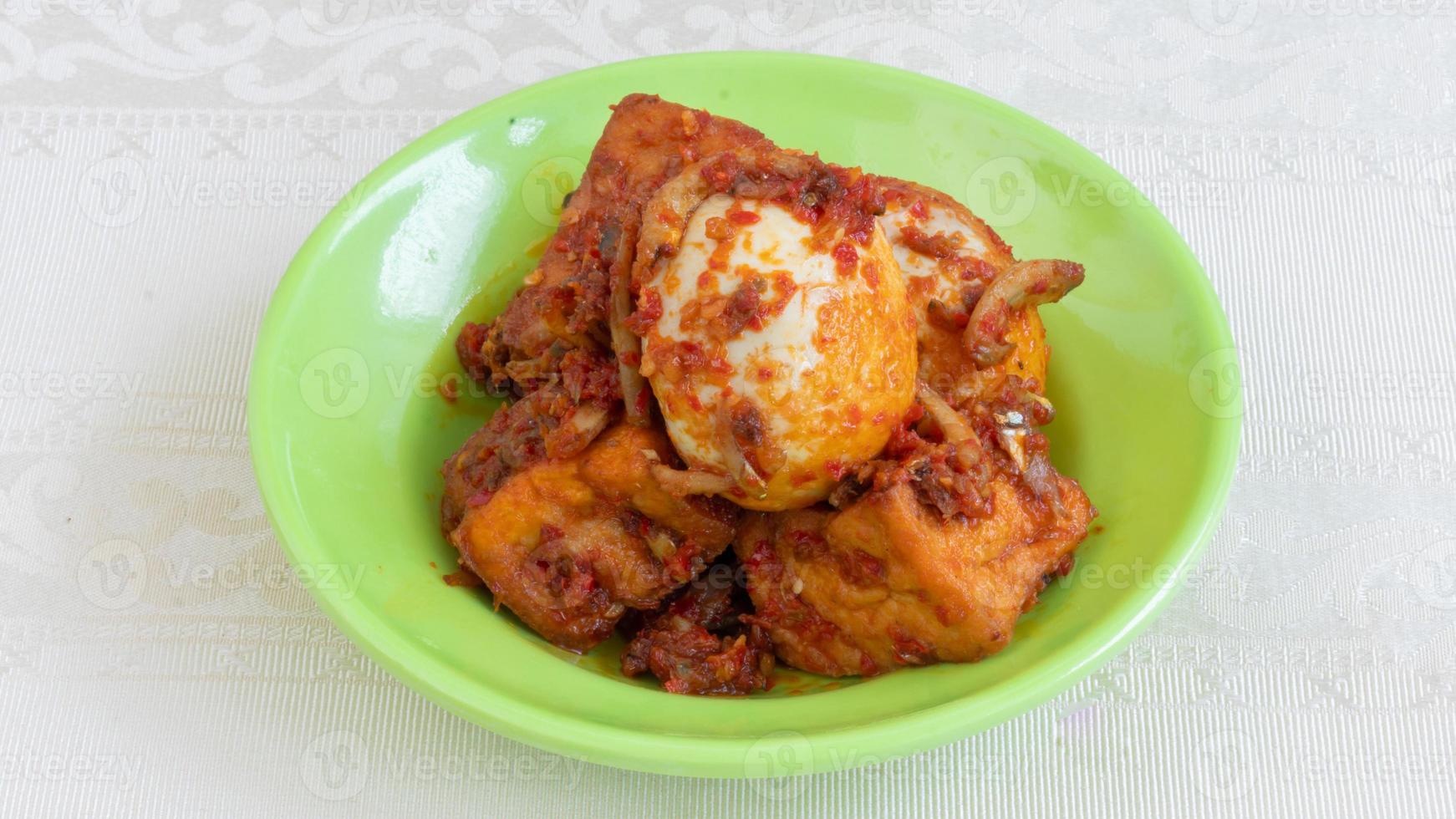 Balado egg sauce, chili sauce filled with eggs, anchovies, and tofu. Served in a bowl on a gray background. Selected focus. photo