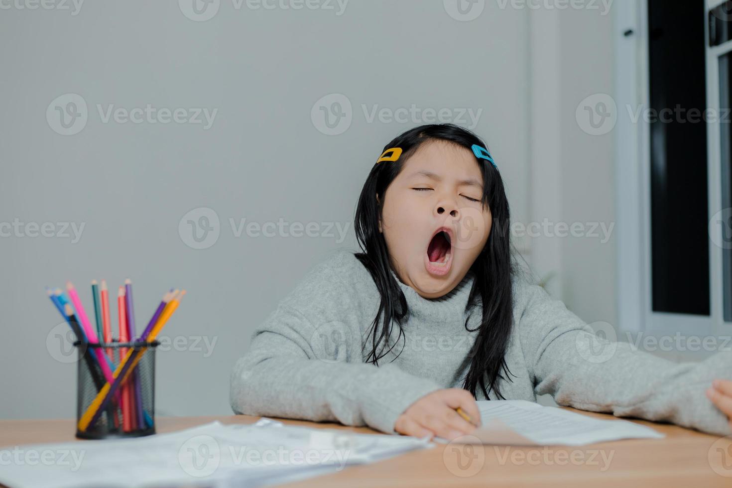 chica asiática bostezando mientras trabaja en un escritorio foto