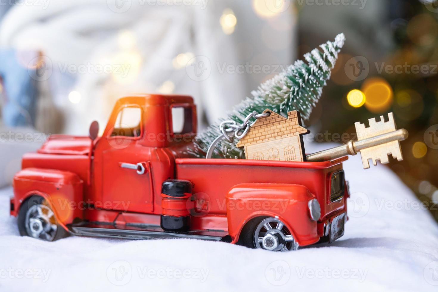 Red retro car with a Christmas tree decorates with the house key in the pickup truck for Christmas. Buying a home, moving, mortgage, loan, real estate, festive mood, New Year photo