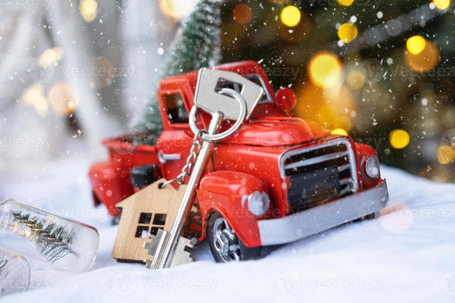 Red retro car with a Christmas tree decorates with the house key in the pickup truck for Christmas. Buying a home, moving, mortgage, loan, real estate, festive mood, New Year photo