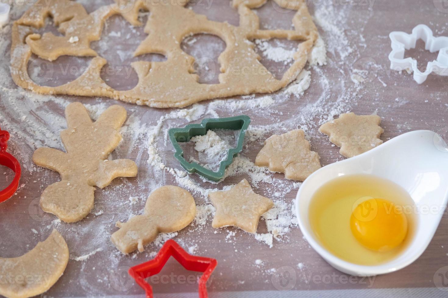 The hands of mom and daughter close-up cut out cookies from the dough with molds on a Christmas theme in the form of a snowman, a Christmas tree, stars photo