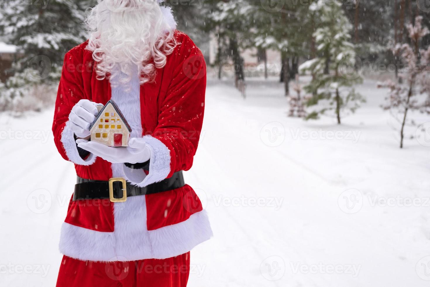 House key with keychain cottage in hands of Santa Claus outdoor in snow. Deal for real estate, purchase, construction, relocation, mortgage. Cozy home. Merry Christmas, new year booking event and hall photo