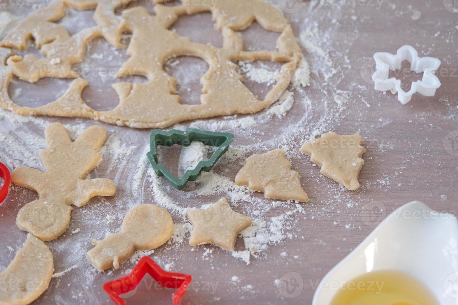 The hands of mom and daughter close-up cut out cookies from the dough with molds on a Christmas theme in the form of a snowman, a Christmas tree, stars photo