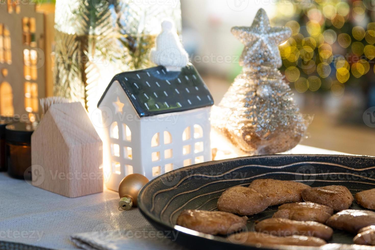 decoración navideña festiva en la mesa, pasteles caseros para el desayuno, galletas de panadería. hogar acogedor, árbol de navidad con guirnaldas de luces de hadas. año nuevo, estado de ánimo navideño foto