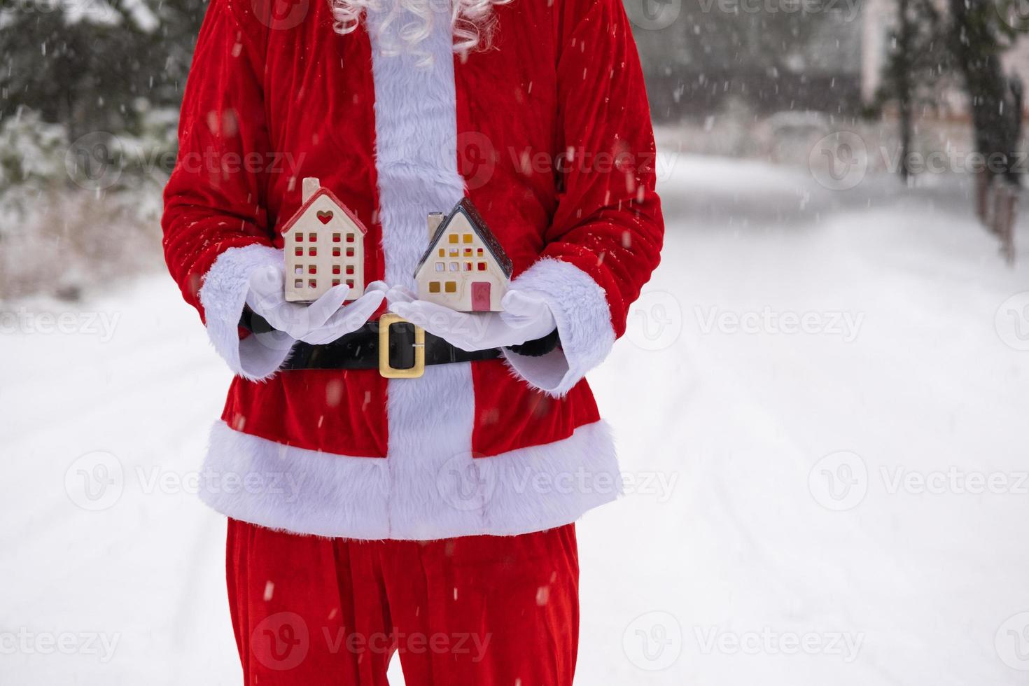 House key with keychain cottage in hands of Santa Claus outdoor in snow. Deal for real estate, purchase, construction, relocation, mortgage. Cozy home. Merry Christmas, new year booking event and hall photo