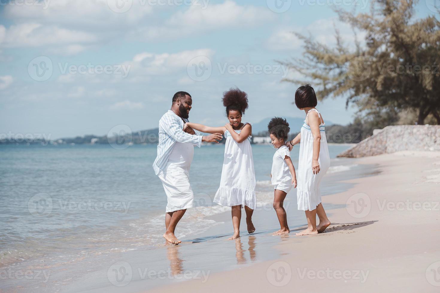 concepto familiar de vacaciones de verano. familia feliz caminando y jugando juntos en la playa foto