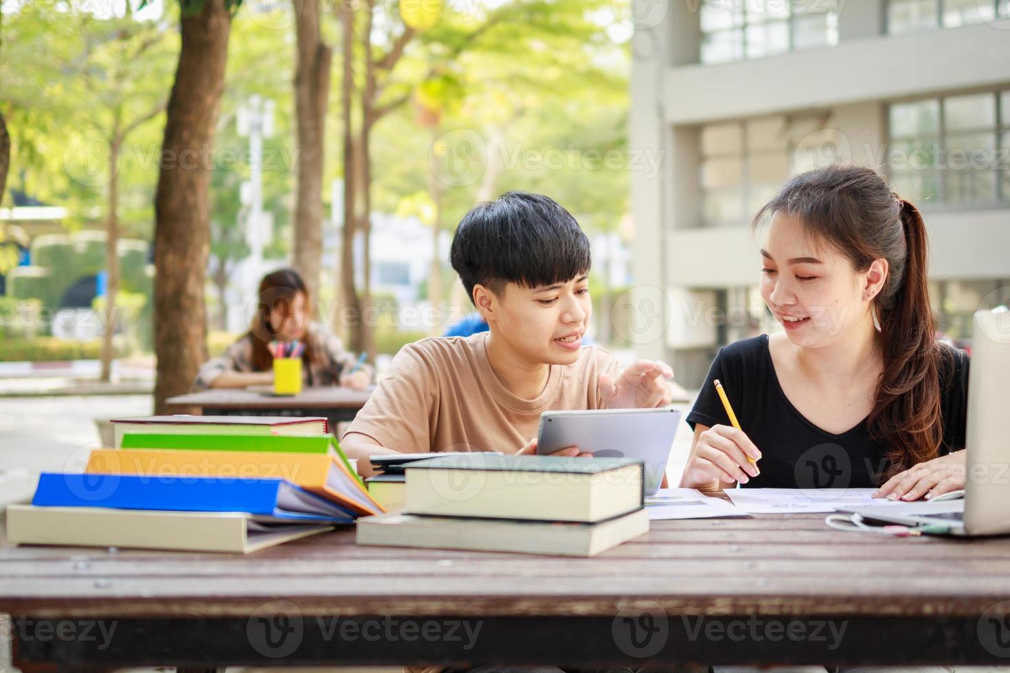 A happy group of attractive young people is tutoring exams with study books photo