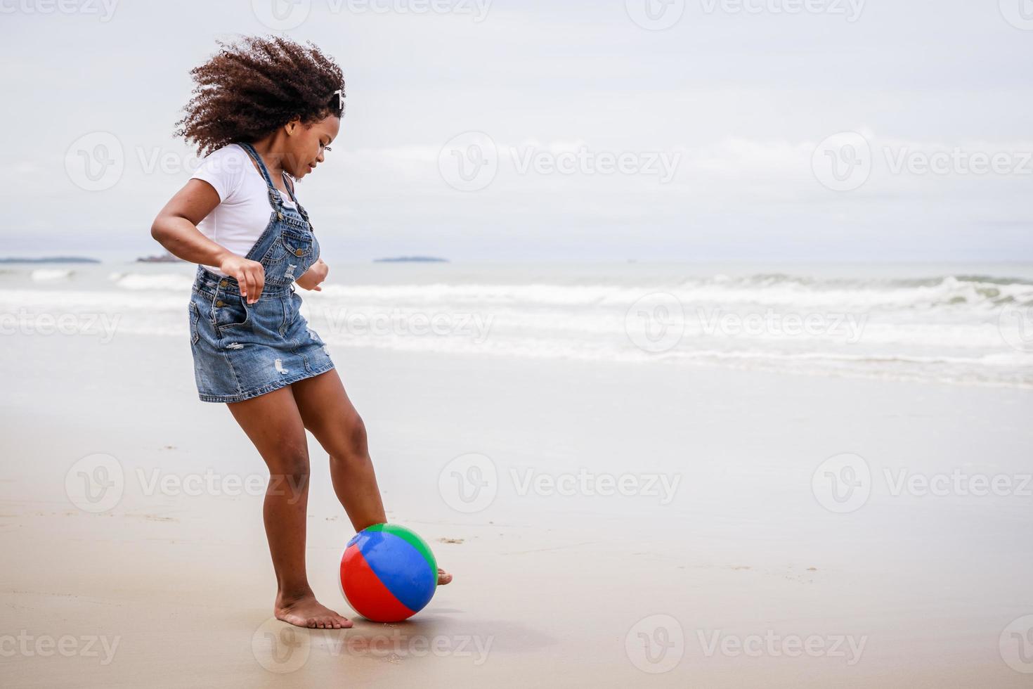 Funny vacation. African American kid girl playing ball and having fun on a tropical beach photo