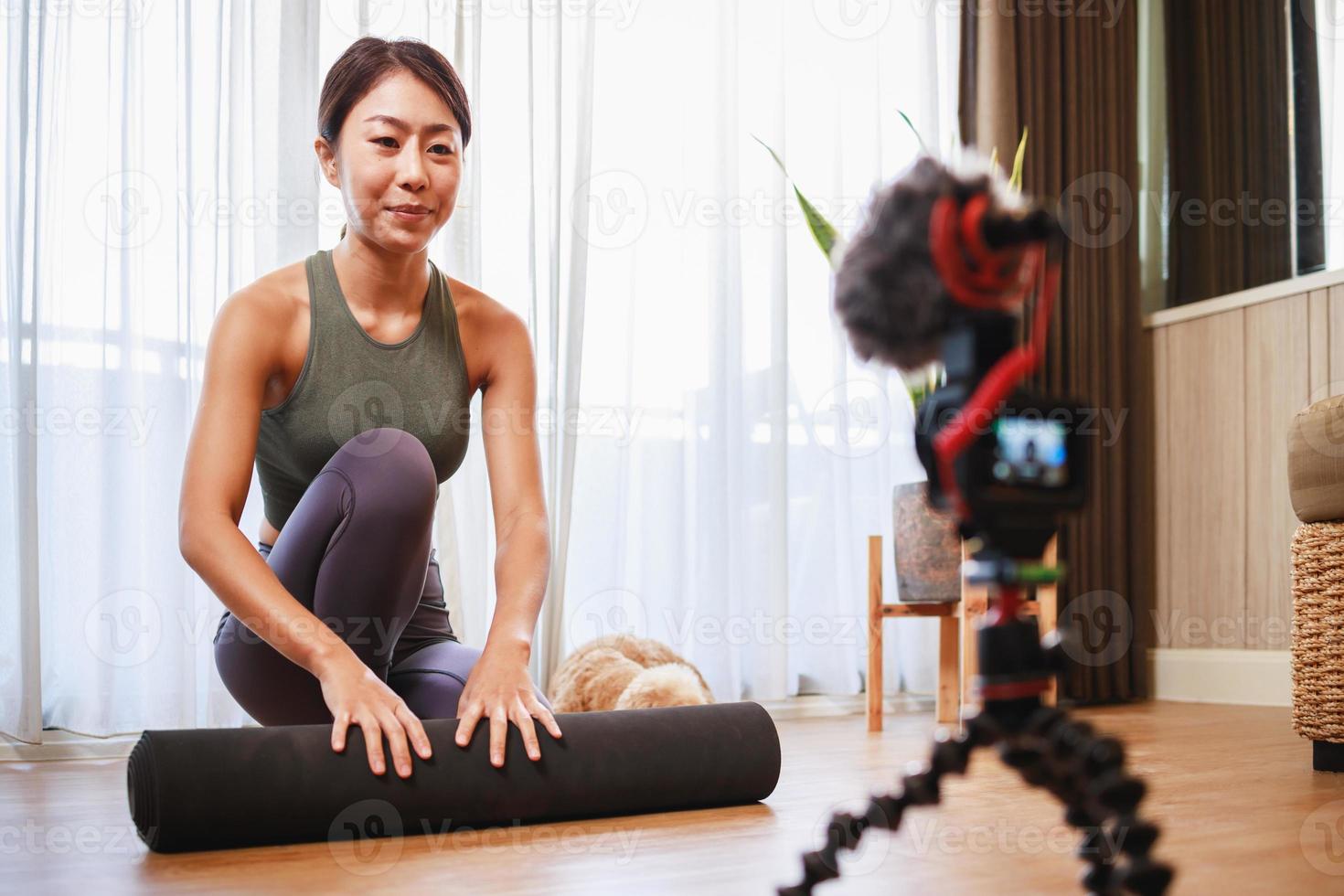 profesora de yoga asiática filmando una clase de yoga en línea en video para las redes sociales. foto
