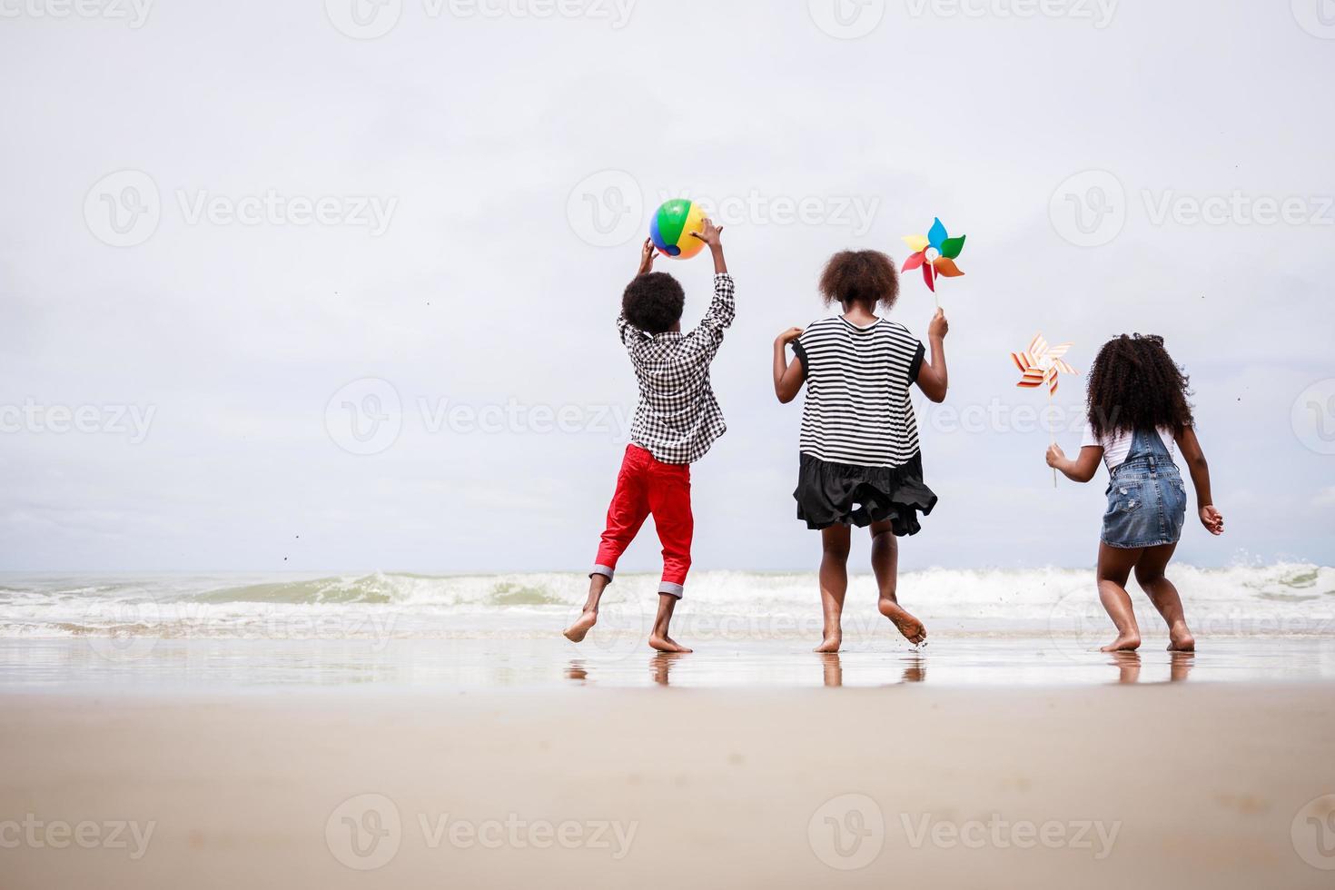 grupo de diversidad de niños afroamericanos juega en una playa tropical. concepto étnicamente diverso foto