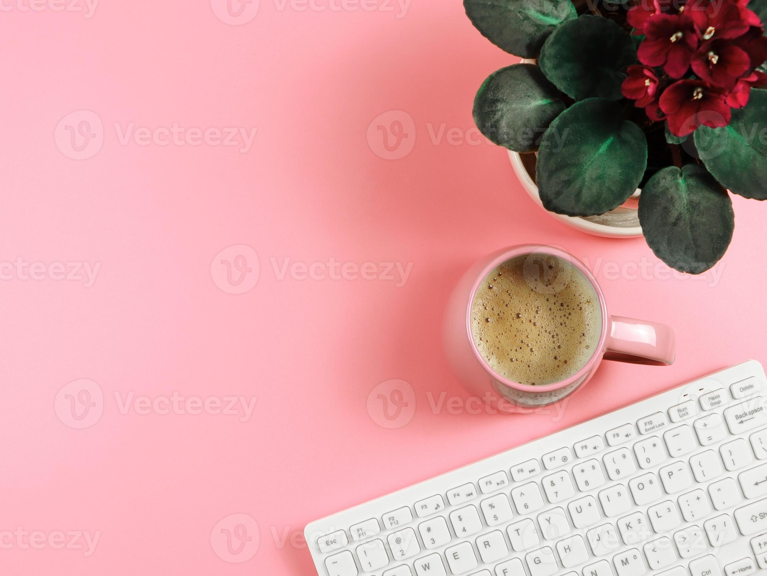 flat lay of computer keyboard, pink coffee cup and African violets in