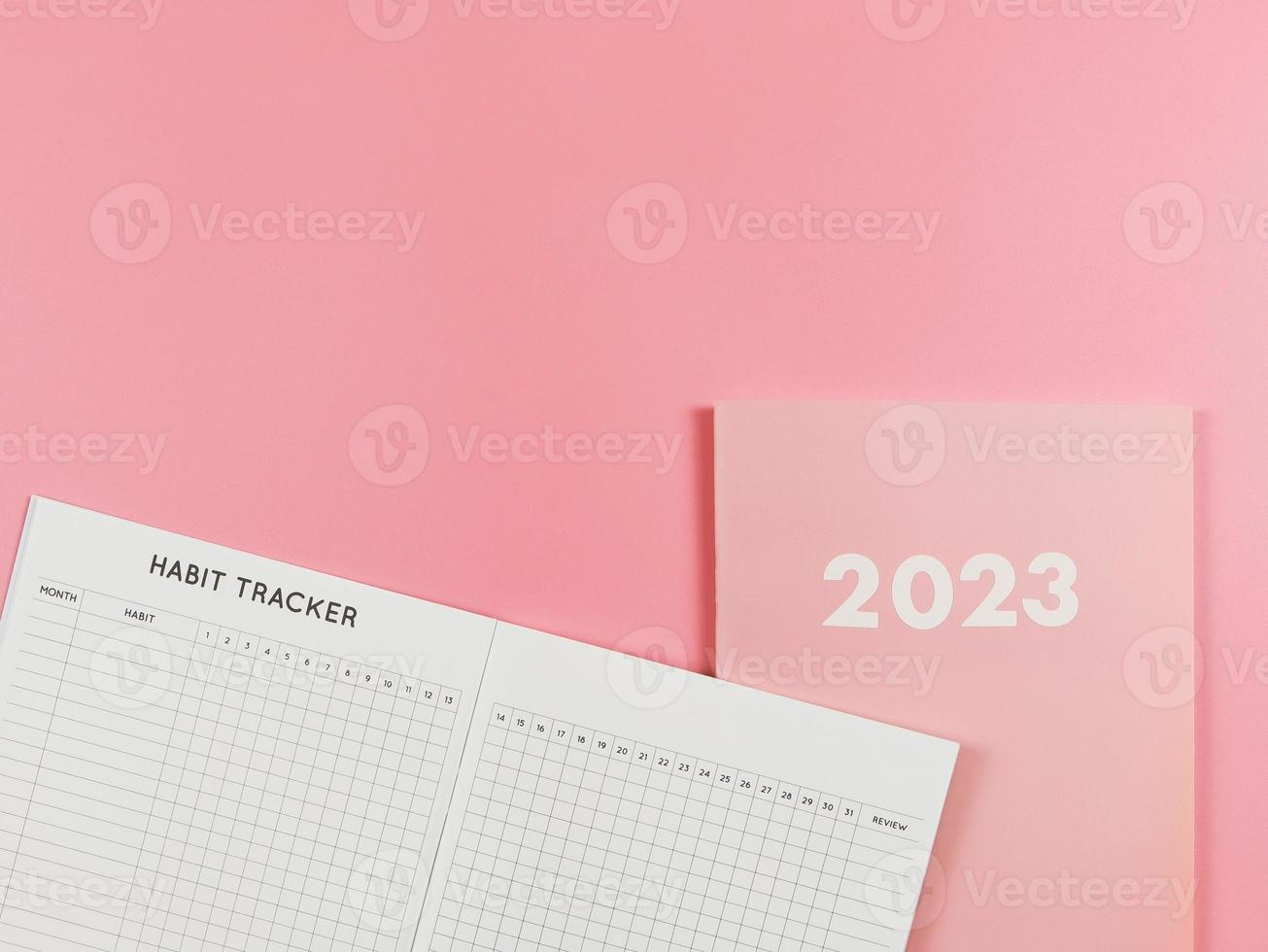 flat lay of habit tracker book on pink diary or planner 2023 on pink background with copy space. photo