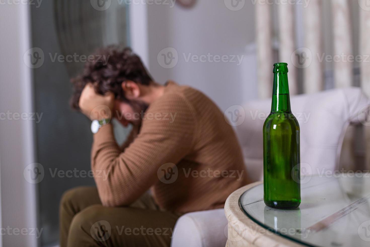 Depressed sad young addicted man feeling bad drinking beer alone at home, stressed frustrated lonely drinker alcoholic suffer from alcohol addiction having problem, alcoholism concept photo