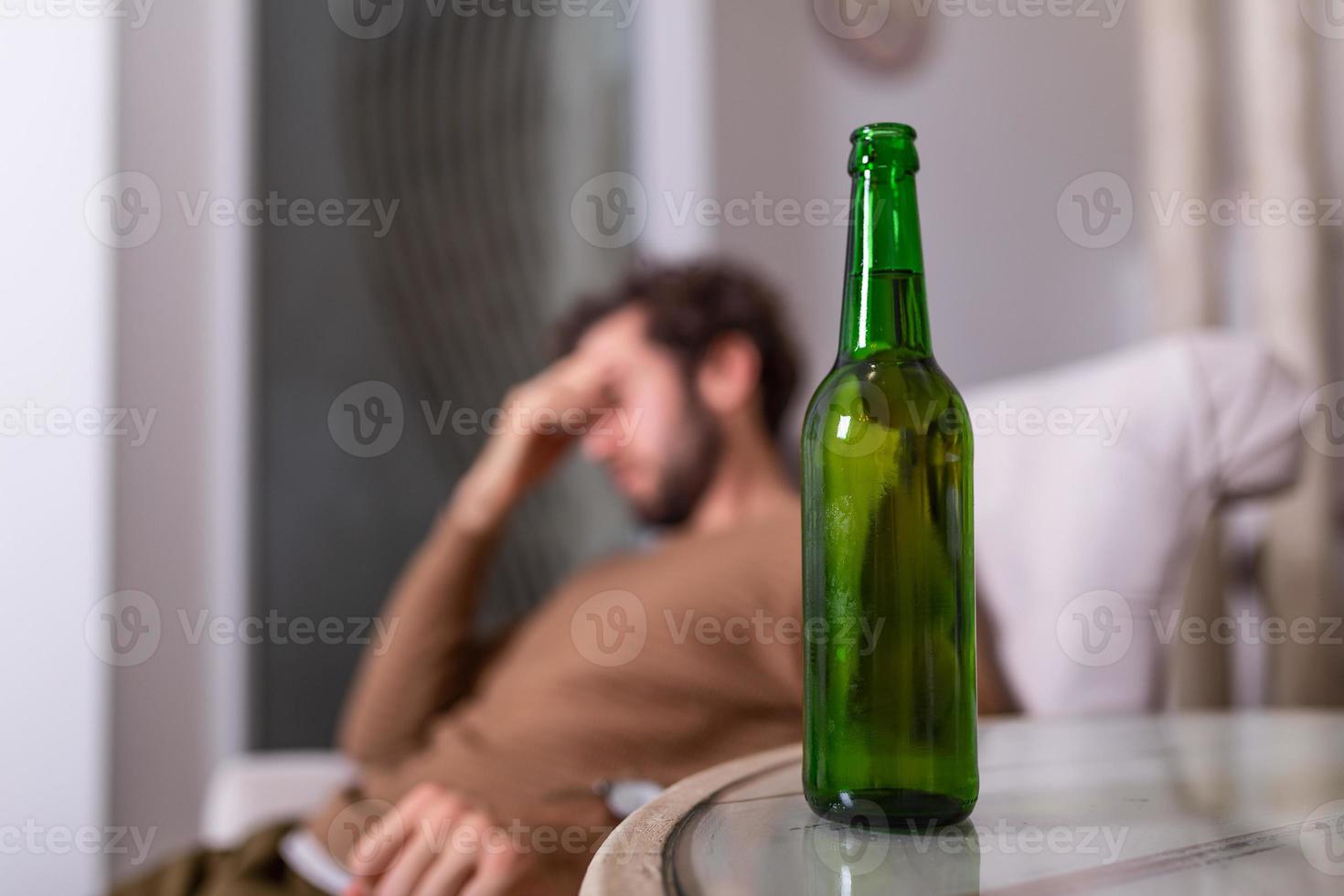 Silhouette of anonymous alcoholic person drinking behind bottle of alcohol. Man fighting with alcoholic habits, drink sitting on sofa at home photo