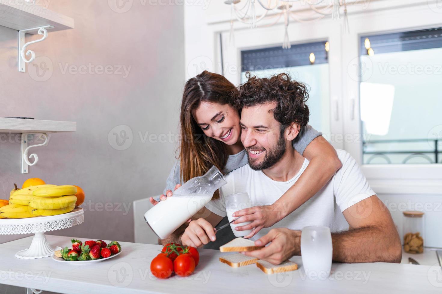 Romantic young couple cooking together in the kitchen,having a great time together. Man and woman laughing and drinking milk in the morning with breakfast photo